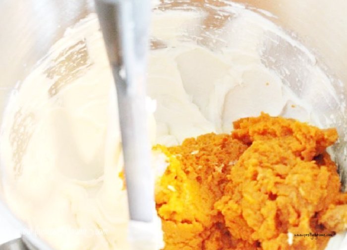 A large mixing bowl filled with cream cheese and pumpkin puree for no bake pumpkin cheesecake.