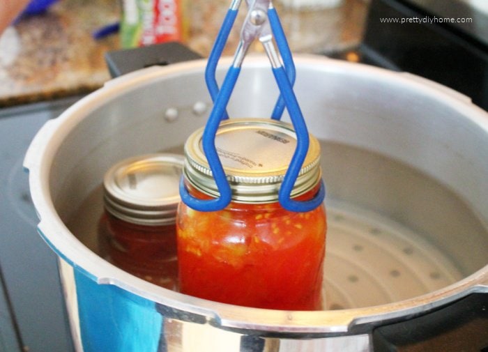 Removing hot canned tomatoes from the canner to cool.