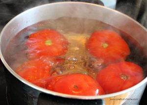 A large pot of tomatoes being boiled to remove the skins.