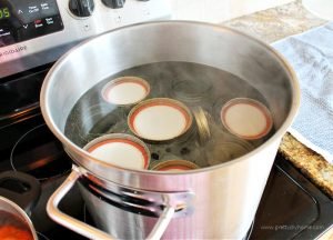 A large pot filled with canning jars, lids and rings that are being sterilized in boiling water.