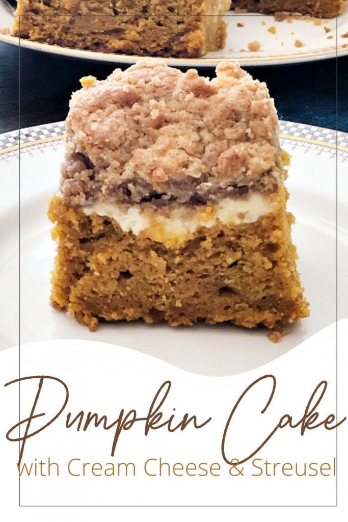 A thick slice of pumpkin cake that has a layer of cream cheese and a streusel topping.