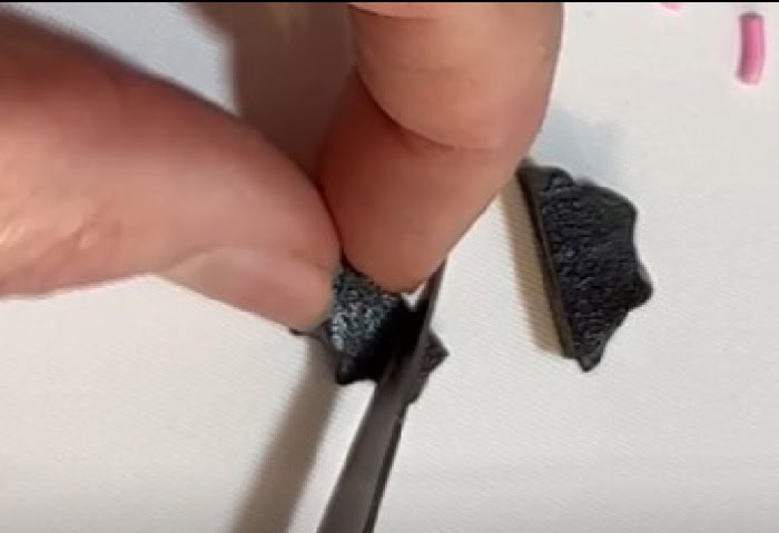 Cutting black licorice into small pointed fangs for Halloween monster pretzels.