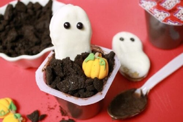 Chocolate pudding cups decorated with little cookie ghosts and candy pumpkins to be mini graveyards.