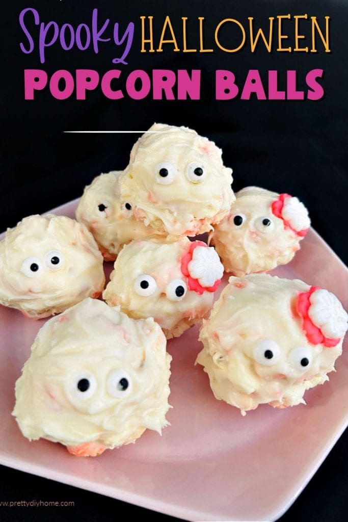 A tray of Halloween popcorn balls that look like little ghosts with eyeballs and flowers.