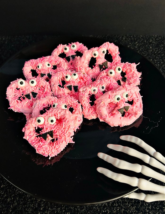 A dozen Halloween pretzels in candy coating with eyeballs and candy fangs.