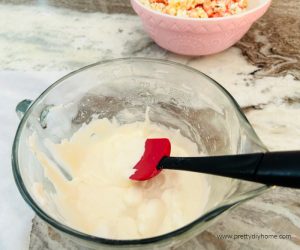 Stirring melted marshmallows in a large bowl for popcorn balls.