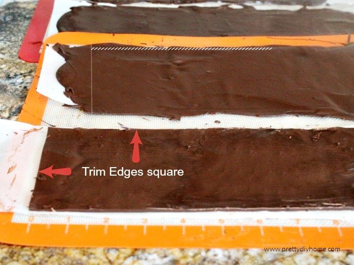 Pouring chocolate onto parchment paper and cutting the edges to make a chocolate cake collar.