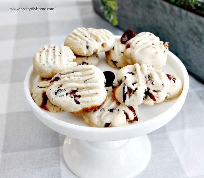 A white pedestal tray covered with a shortbread cookie recipe with chocolate chips, pecans, and rolo bits.