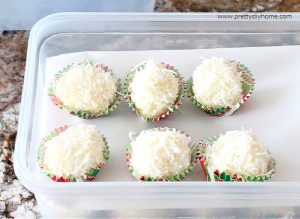 Storing a recipe for coconut balls , each coconut snowball is in a paper wrapper, and placed in a plastic container with parchment paper between layers.