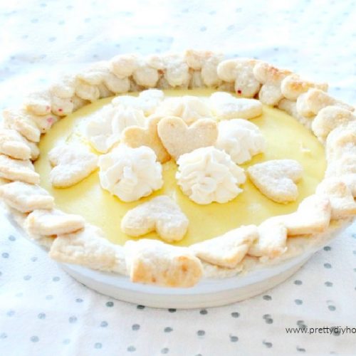 A mixed berry pie covered with lemon custard and sugared Valentine shaped bits of pie crust and whipping cream..