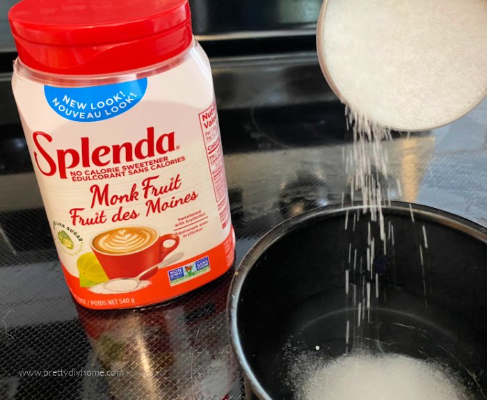 A small pot with water on the stove with monk fruit sweetener being added to it.