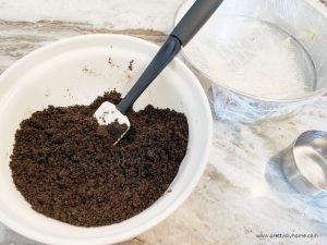 Making a oreo cookie crust with oreo cookies and butter. There is a springform ice cream cake pan.