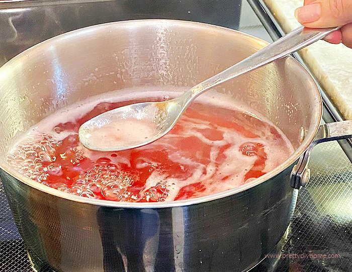 Skimming the froth off of a pot of cooking rhubarb juice for making syrup.