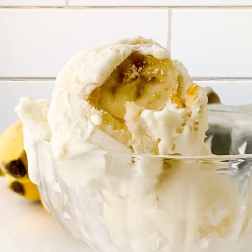 A large bowl filled with homemade no churn ice cream with banana slices and cookie bits for crunch.