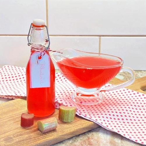 A bottle filled with homemade rhubarb syrup recipe and a bowl of rhubarb syrup beside it.