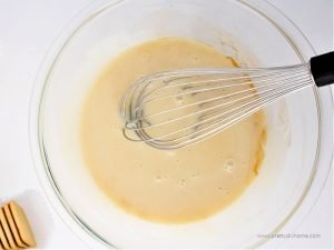 A bowl of sweetened condensed milk and vanilla for making ice cream. The condensed milk has a whisk in it for beating.