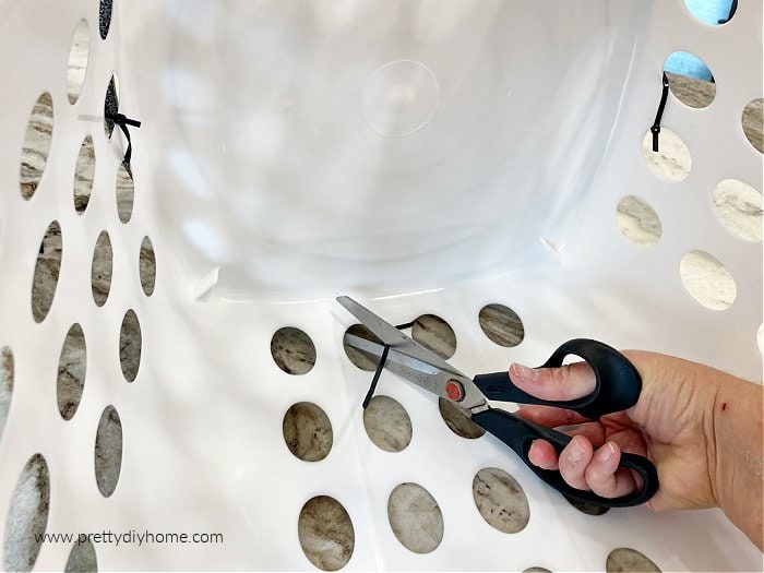 Cutting off a black zip tie tail inside a basket used for pantry storage.