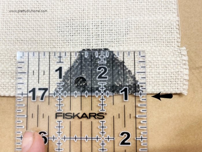 A one inch rolled hem on fabric with a ruler showing one inch.