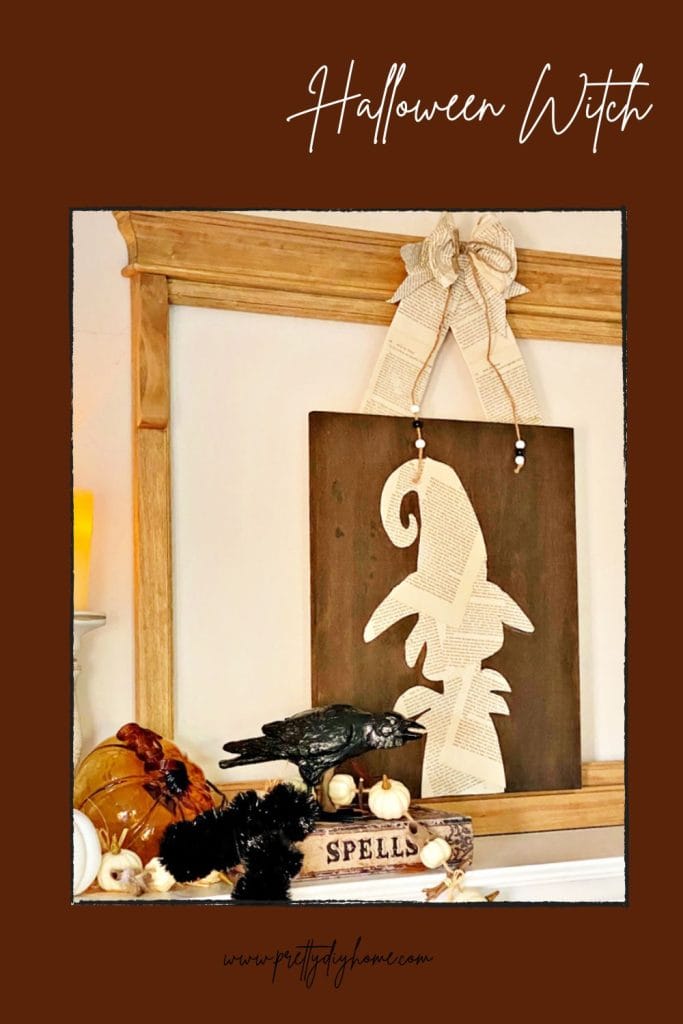 A Halloween witch decoration made using a wood dollar store back and book pages.  Its a witch silhouette made with book pages sitting on a Halloween mantel with a crow and black magic book beside it.