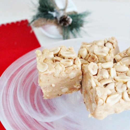 Homemade payday candy bars sitting on a white plate. An easy to make no bake Christmas recipe. A chewy peanut butter budge surrounded by layers of salty peanuts.