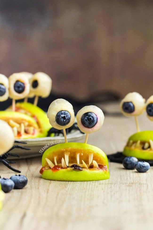 Two apple slices forming a mouth with almond slices for teeth, strawberry jam for blood, while eating dried cranberries. They then have very cute eyes made using bits of banana and blueberry eyeballs.