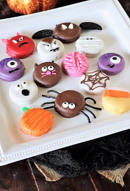 A white plate covered with 12 easy and fun ways to decorate the cookies.  There is a white ghost, orange pumpking purple one eyed monster a white mummy spiders. candy corn and a vampire.