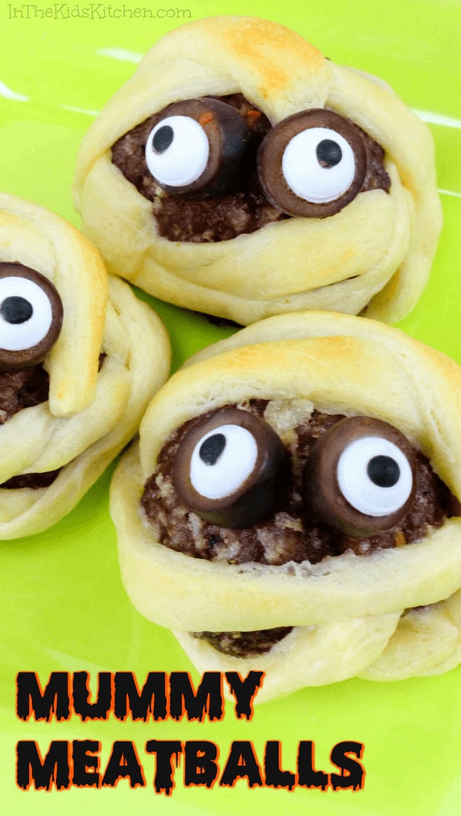 Three mummy meatballs made with hamburger thats wrapped in strips of crescent rolls to resemble mummies and then olives and eddible eyeballs are added to make the face