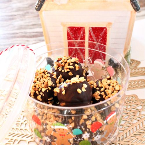 A pretty Christmas container filled to the rim with homemade Nutter Butter Balls. There is a Christmas barn cookie jar in the background.