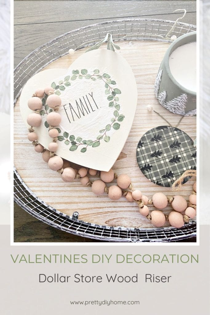 An easy to make Wood Valentines Day Craft using Dollar Store Supplies.  The Valentine is painted white with green eucalyptus leaves on the front.  The little Valentine shaped riser is sitting on a tray surrounded by other neutral decor.