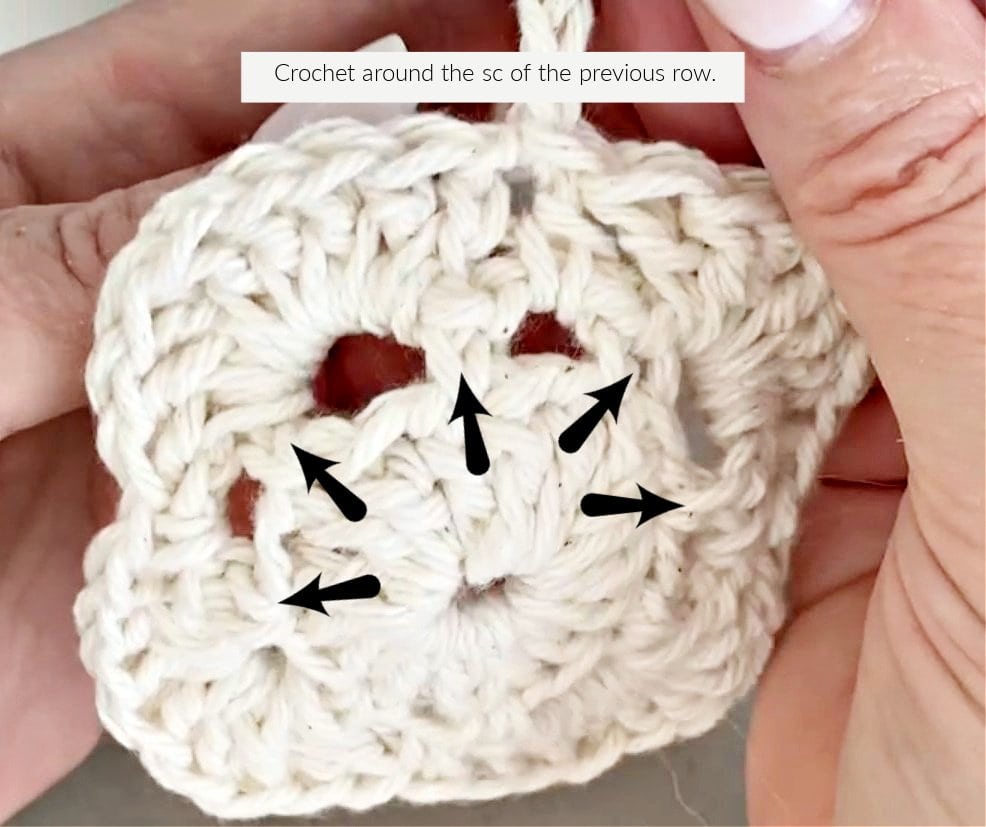 A crochet rose pattern being made, with arrows showing the stitch locations for a SC in the previous row.