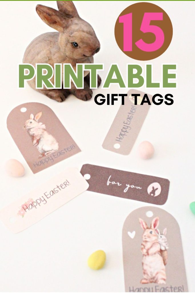 One set of 15 Easter tag free printables.  The printable tags are cut out and laying on a white table with a sweet wooden Easter bunny beside them, and some small chocolate eggs.  The caption says 15 printable gift tags.