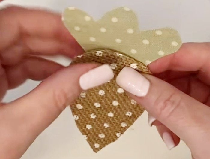 Attaching a green cut out fabric carrot top to the backside of a burlap carrot bottom.