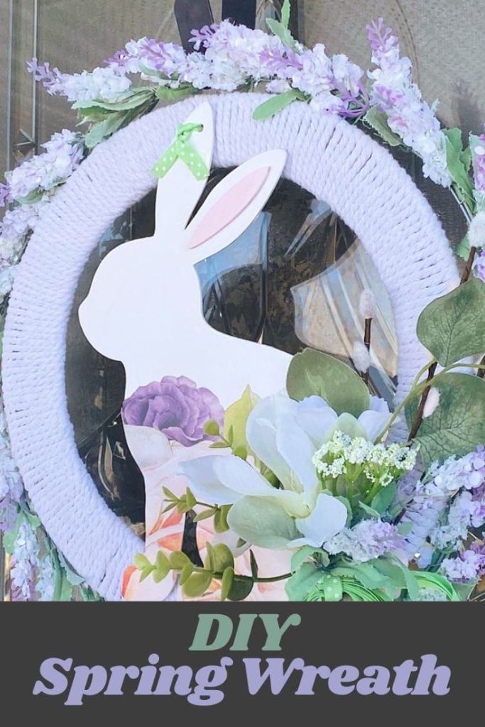 A large Spring with with a wooden bunny on front, white cording encircled with a ring of lavender coloured Spring blossoms.  The wreath is then decorated with a flower arrangement and a large green bow,