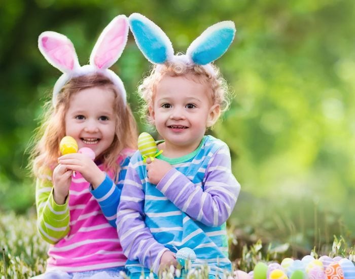 Two young children enjoying an easter egg hunt.