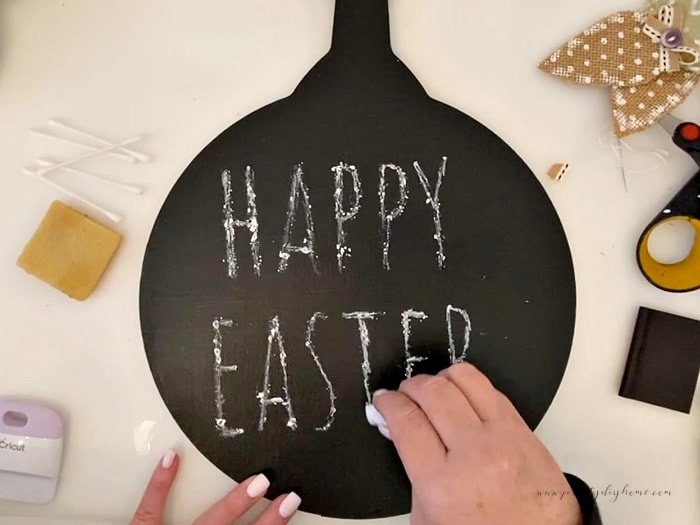 Happy Easter lettering transferred onto the front of a black Easter chalkboard DIY.