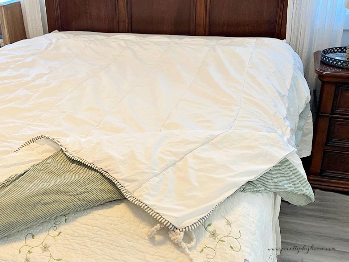 An duvet cover layered with an insert with the corners tied together.  Step one of how to do a burrito roll for adding a cover to a duvet.