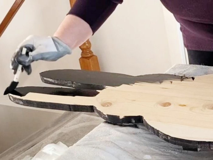 Staining a wooden rabbit shape with a foam brush.