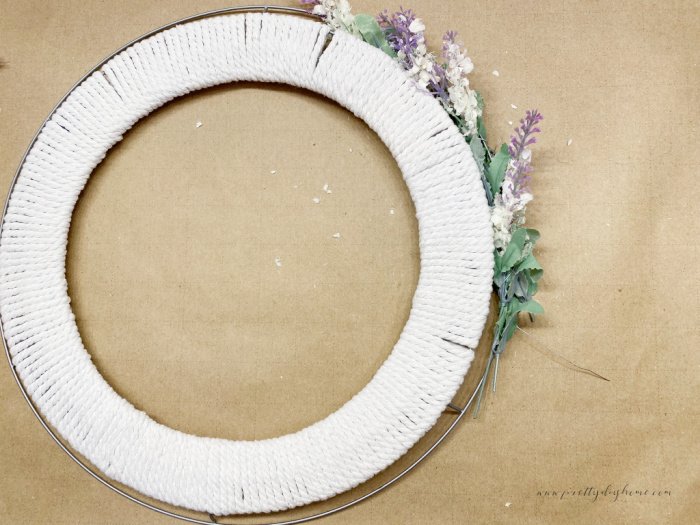 Encircling the outside of a wreath with small purple Spring flowers.  The purple faux flowers act like a frame for the wreath.