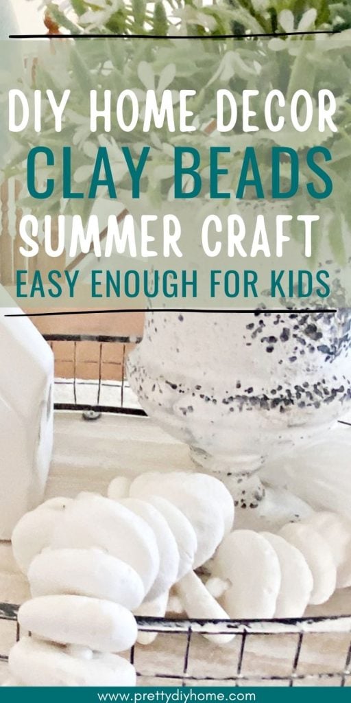 DIY air dry clay beads sitting in an arrangment with a green lamp, a vase with greenery, and a white porcelain house decoration.  The overlay text says DIY Home Decor Clay Beads Summer Craft Easy Enough for Kids.