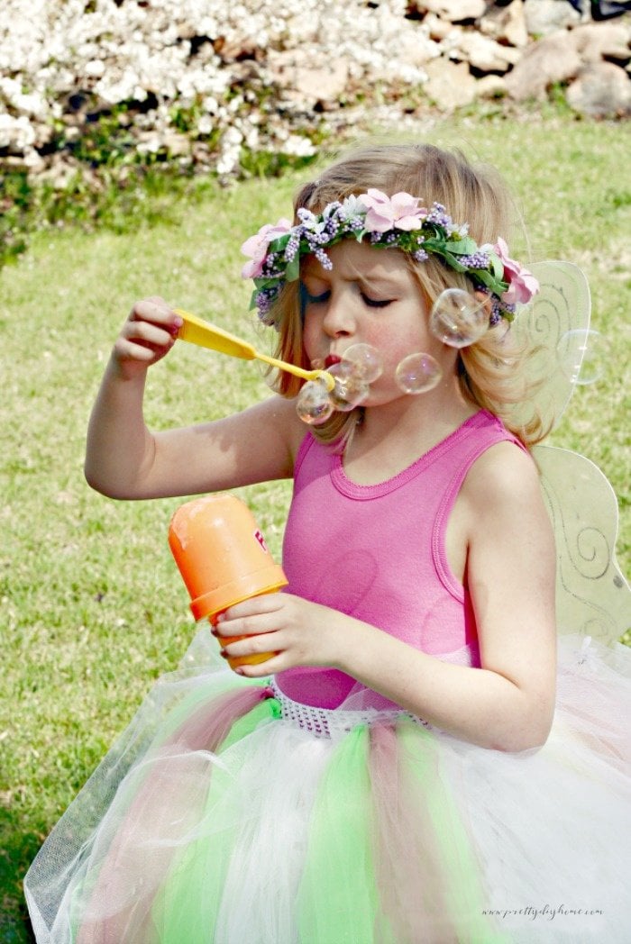 A little girl playing in her no sew tutu skirt. The tutu is long and thick with flowers.