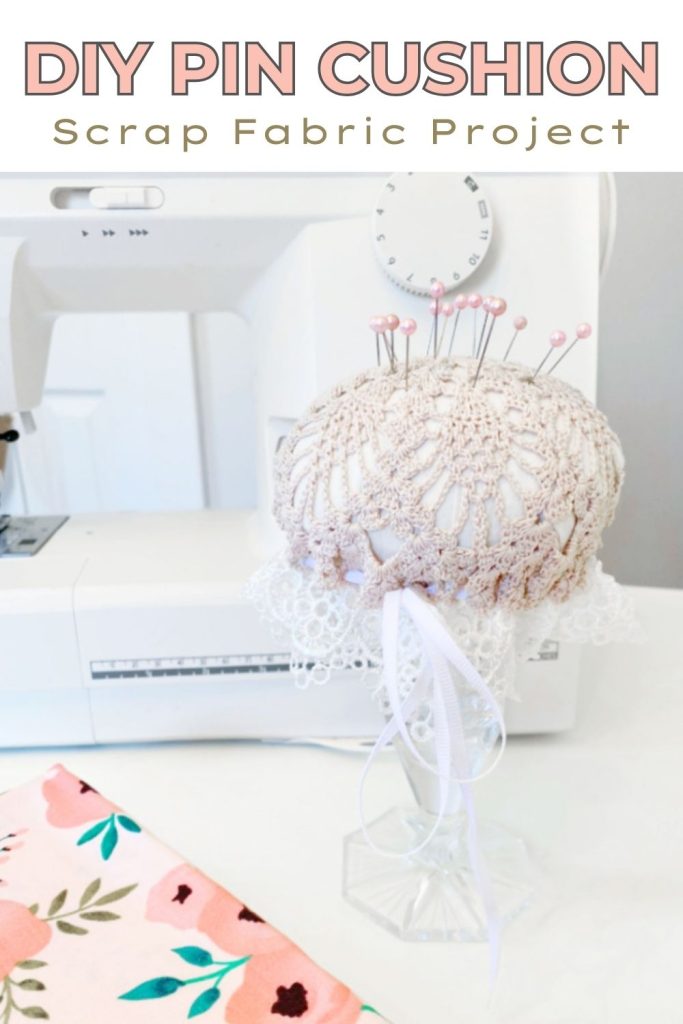 A DIY pin cushion with a ecru lace doily top, and white lace side.  the easy to make fabric pin cushion is attached to a crystal candlestick.