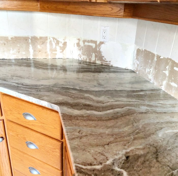 A kitchen backsplash being replaced, where you can see the backboard with the tiles moved.  Its a partially completed DIY tiling backsplash project/