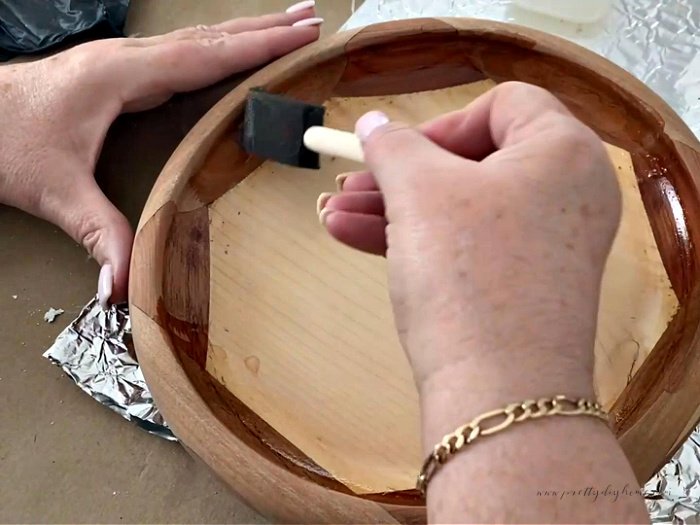 Applying a coat of polyacrylic to protext a wood bowl using a sponge brush.