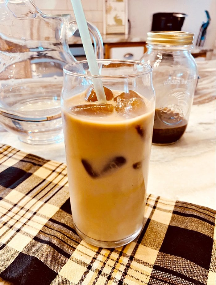 A large class filled with homemade cold brew coffee beign served with oat milk and coffee ice cubes.