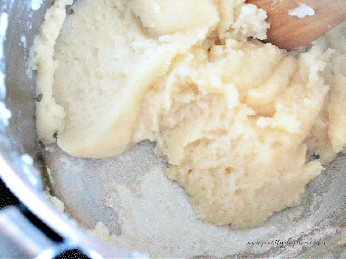 Partially cooked choux pastry being stirred inside a heavy saucepan.