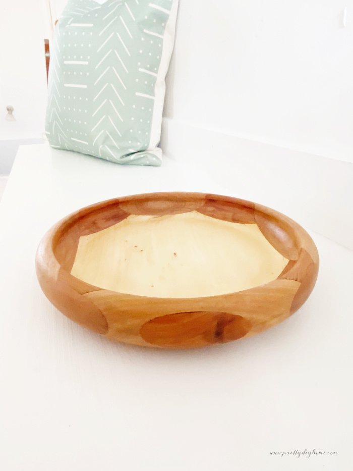 Vintage wood lathe bowl against a white background. You can see all the different natural wood colors of the hardwood.