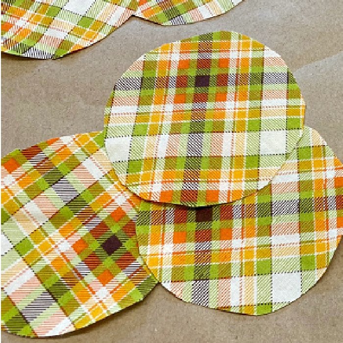 Three circles of cut out plaid fabric for making a flower center.