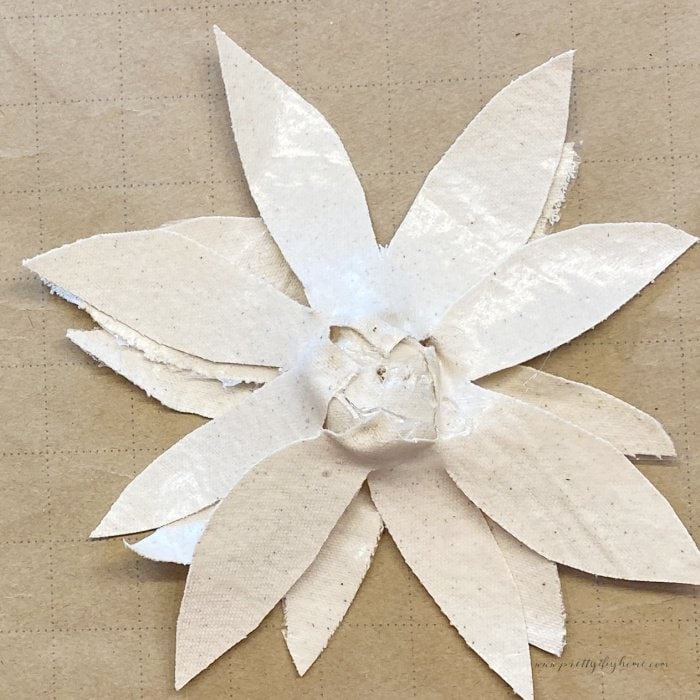 The back side of a fabric flower blossom, showing the placement of the second row of petals.