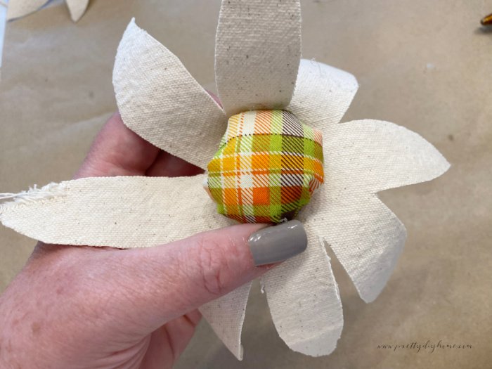 Adding the plaid fabric center of a flower to the petals using hot glue.