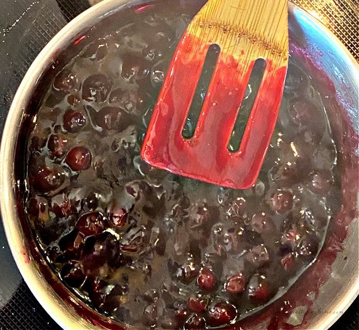 Cooking fresh blueberries on top of the stove into a thick and juicy topping for cream cheese pie.